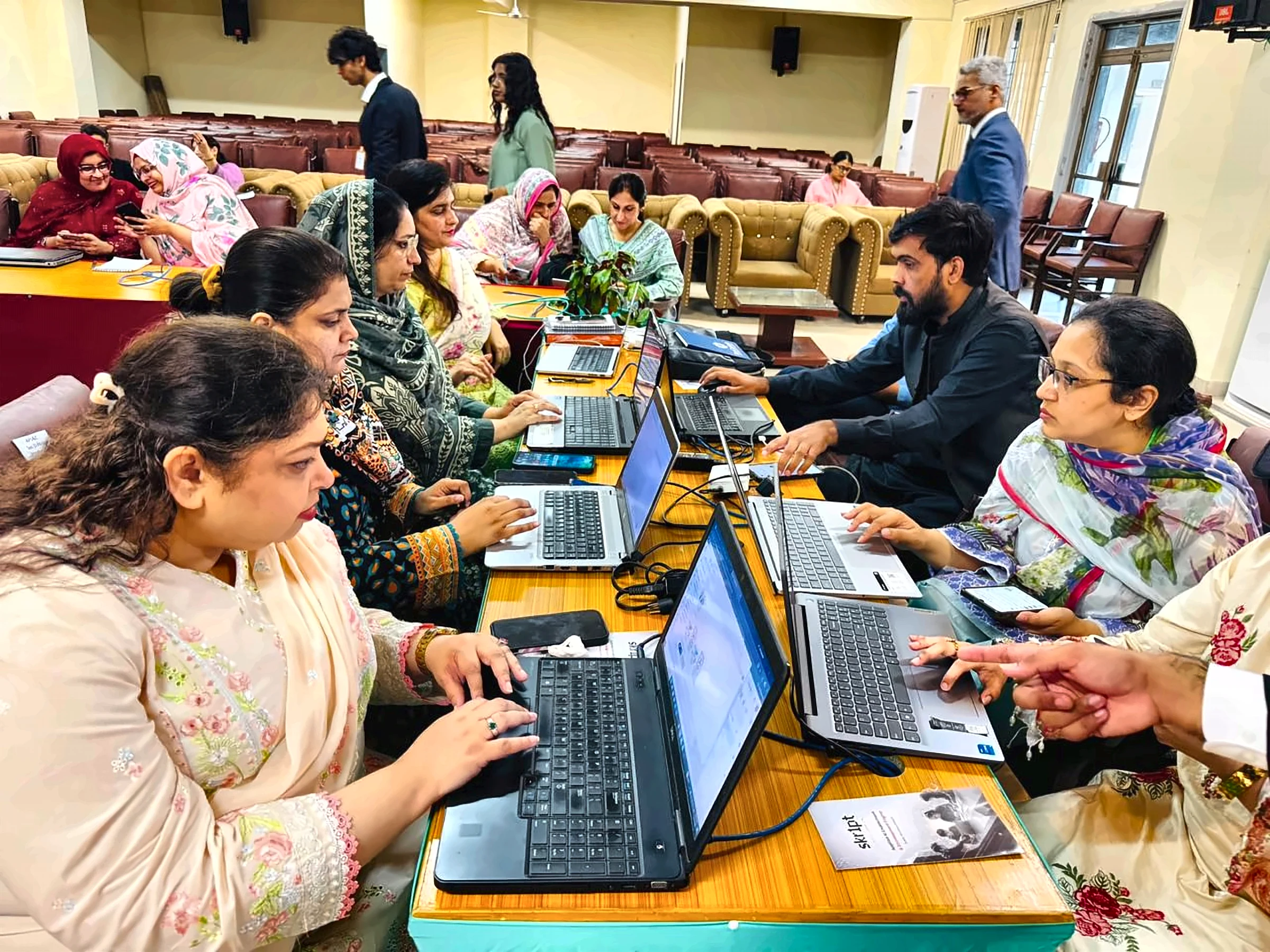 Teachers working on laptops during a live skr1pt AI training session at APSAC DHA II